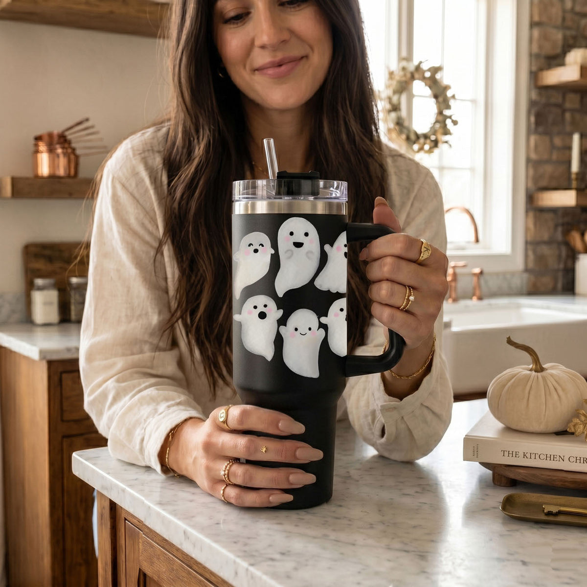 Black 40oz tumbler with ghost pattern, clear lid, and drinking straw in hand