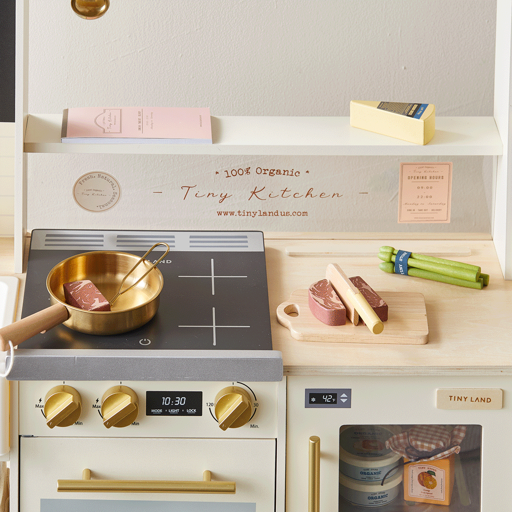 Close-up of play kitchen stovetop with cookware and accessories on counter