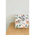 Floral gift wrapping paper with orange fruit and green leaves, tied with string, tag.