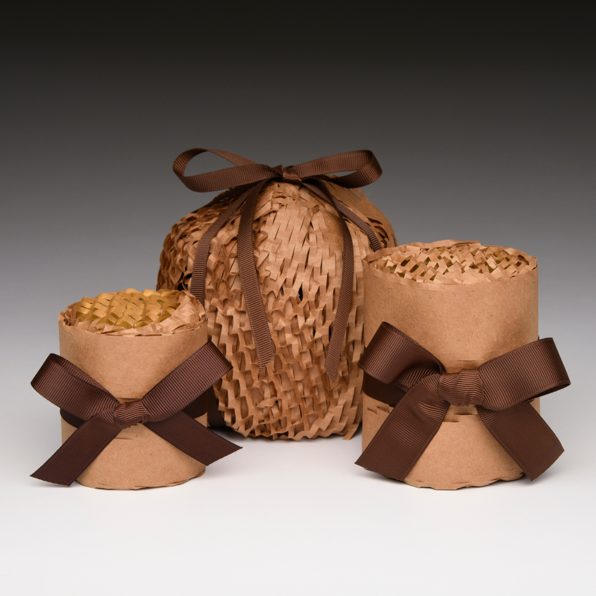 Raffia-wrapped gift candle holder with brown ribbon bows and paper wrap