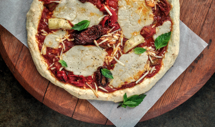 Gluten-free pizza with tomato sauce, cheese, onions, and basil