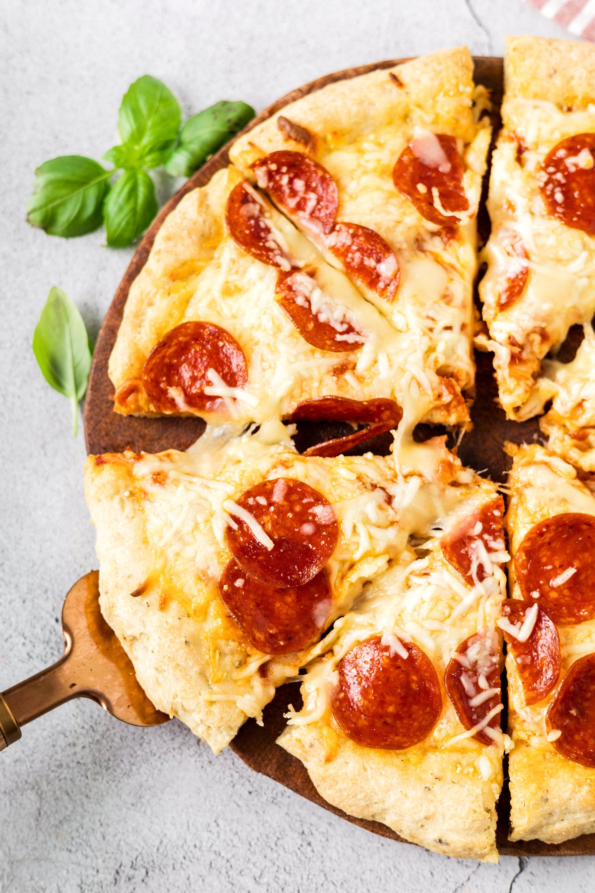Gluten-free pizza slices partially cut, with pepperoni and melted cheese
