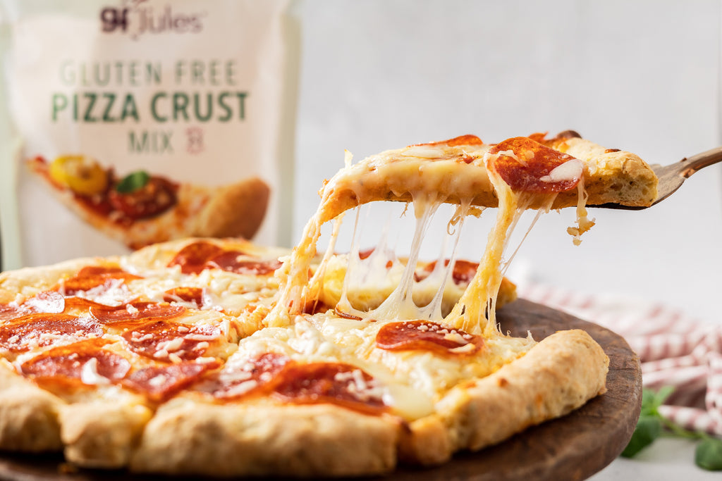 Cheese-pulled slice of gluten-free pizza on a tray, with pepperoni and sauce