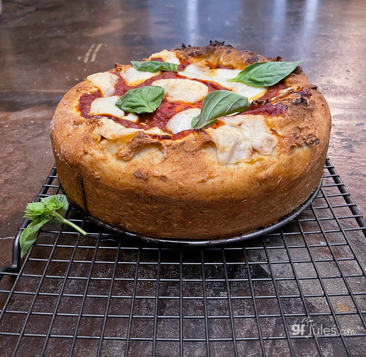Baked gluten-free pizza round with mozzarella, basil leaves, and tomato slices