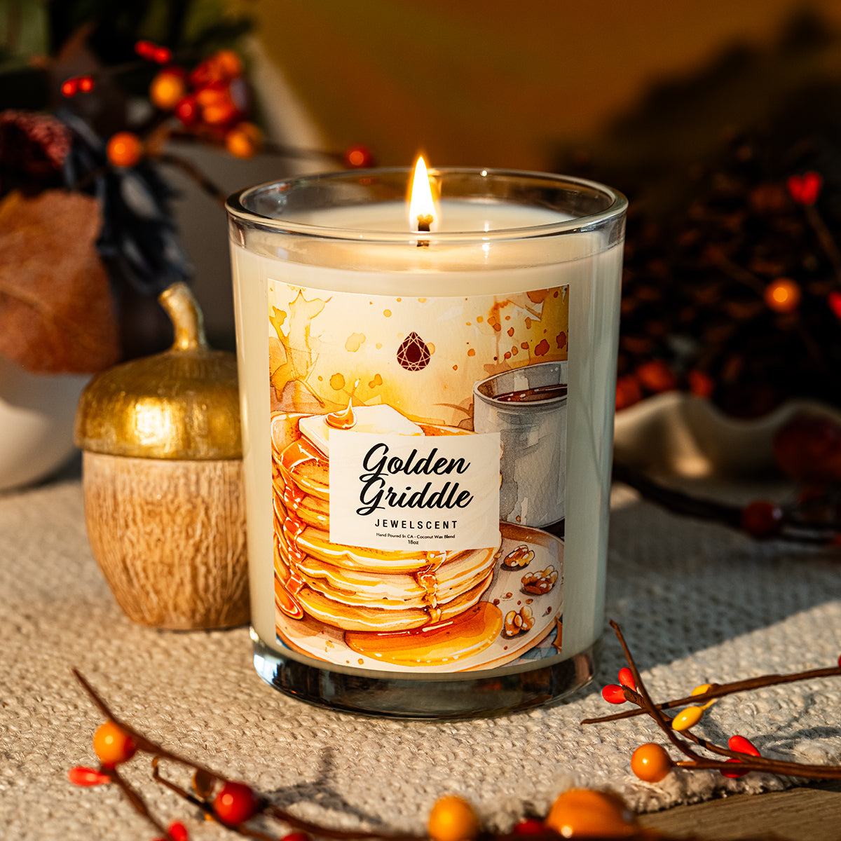 Golden Griddle jewelry candle in clear glass jar, lit flame