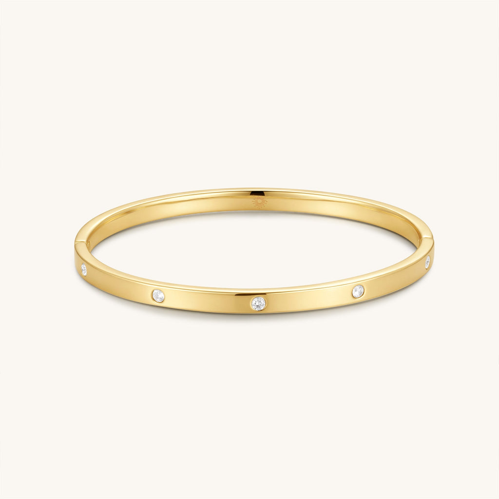 Gold-tone hinged bangle with small round diamond accents, open oval silhouette