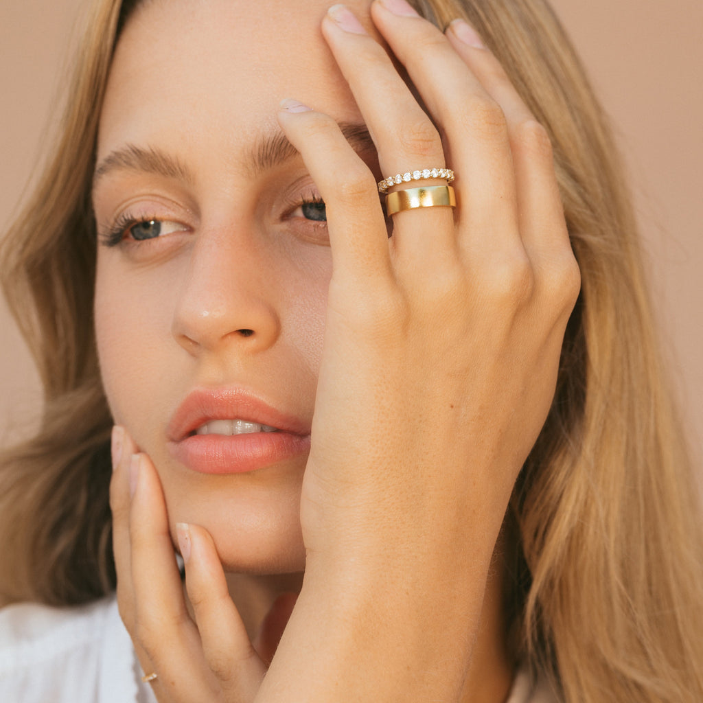 Gold eternity ring with a row of clear stones, worn on finger