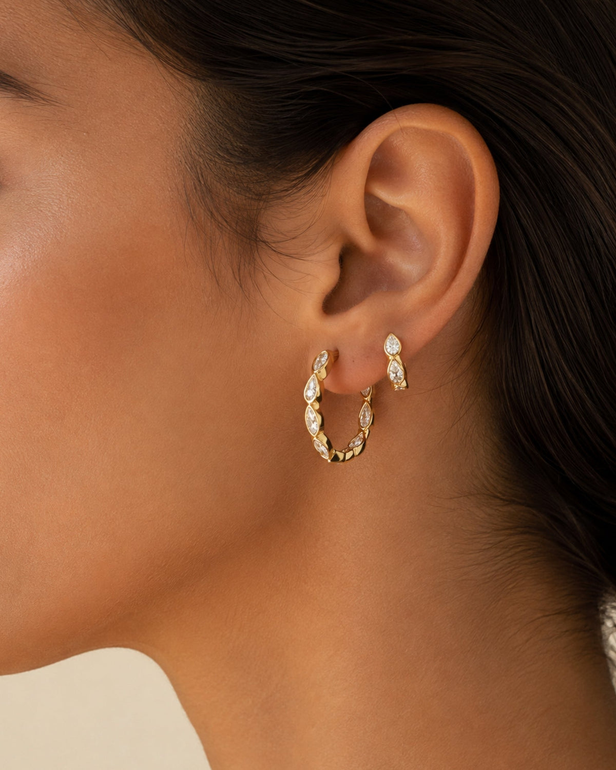 Gold marquise hoop earrings with oval crystal rows on ear