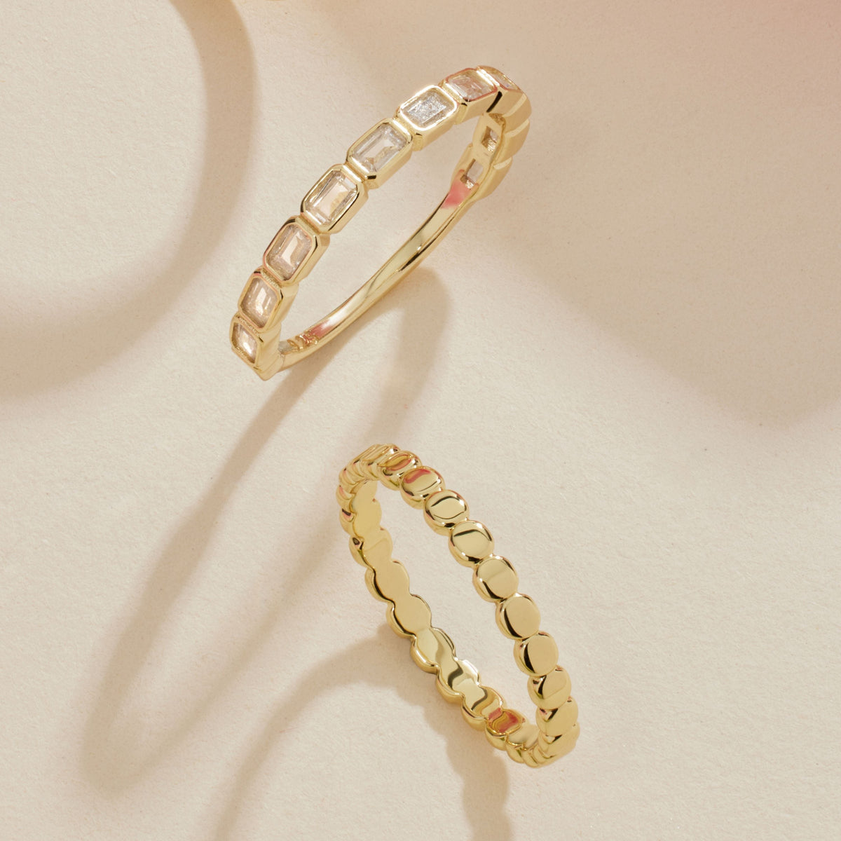 Gold-tone rings laid flat, one eternity band with rectangular clear stones