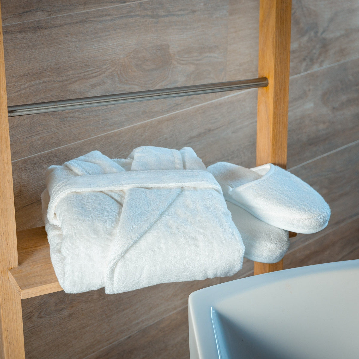 White bathrobe and matching slippers arranged on a bathroom shelf