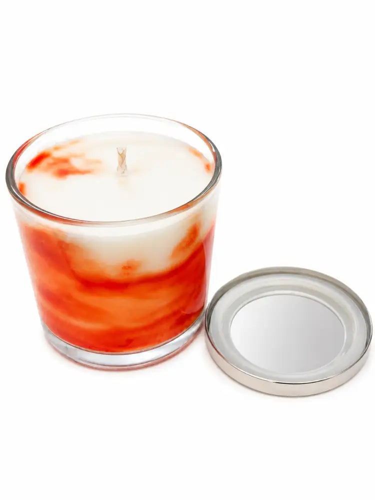 Pumpkin marbled candle in clear glass jar, metal lid removed, visible wick flame