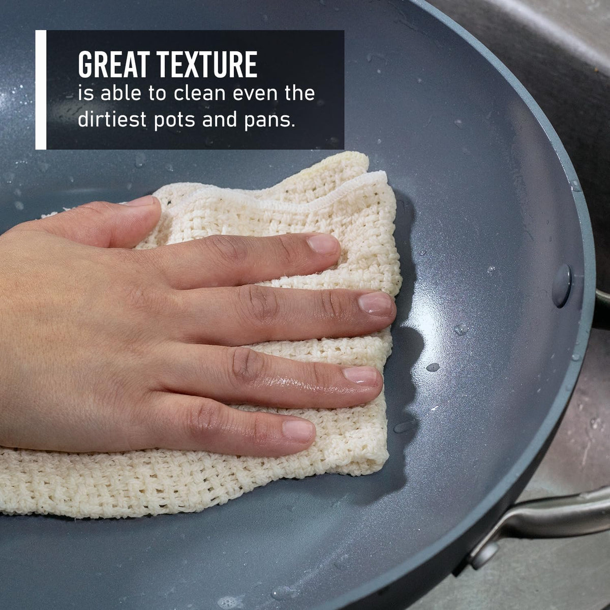 White cotton dishcloth scrubbing a nonstick pan surface