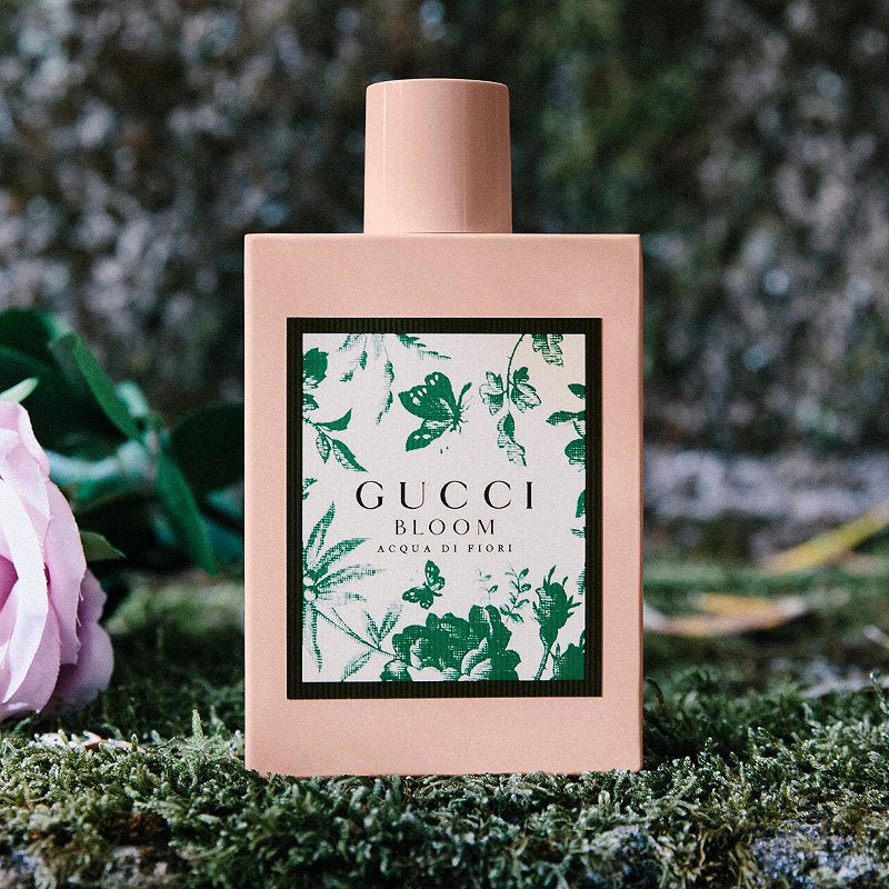 Pink perfume bottle outdoors with Gucci Bloom green floral label