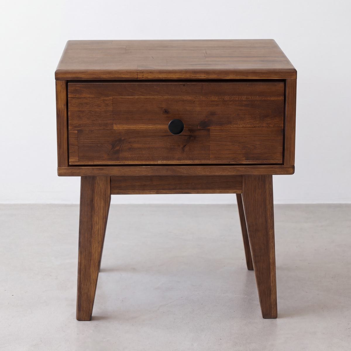 Chocolate wood nightstand with one drawer and round black knob, tapered legs
