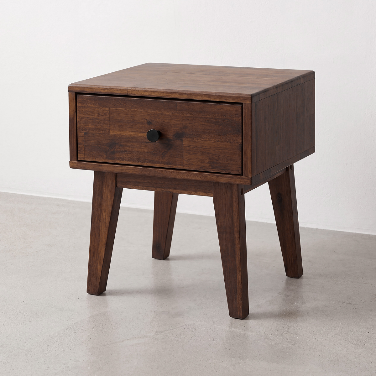 Caramel wood nightstand with one drawer and round black knob, tapered legs