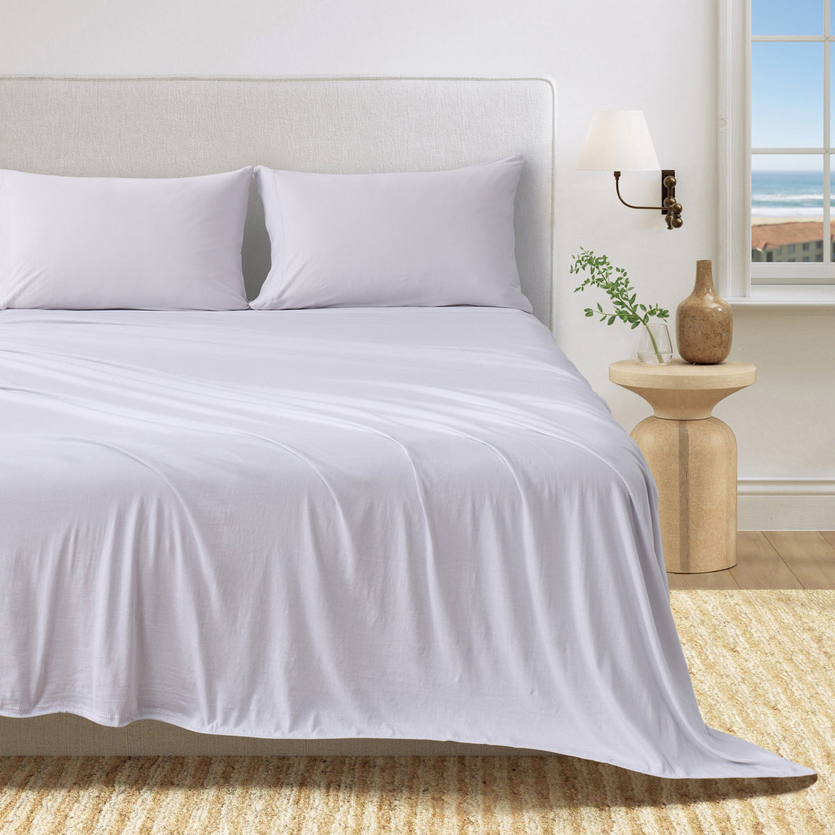 Organic cotton jersey sheet set on bed with pillows, white