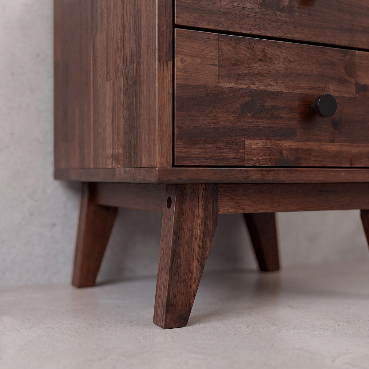 Close-up of solid wood nightstand drawer fronts and tapered wooden legs