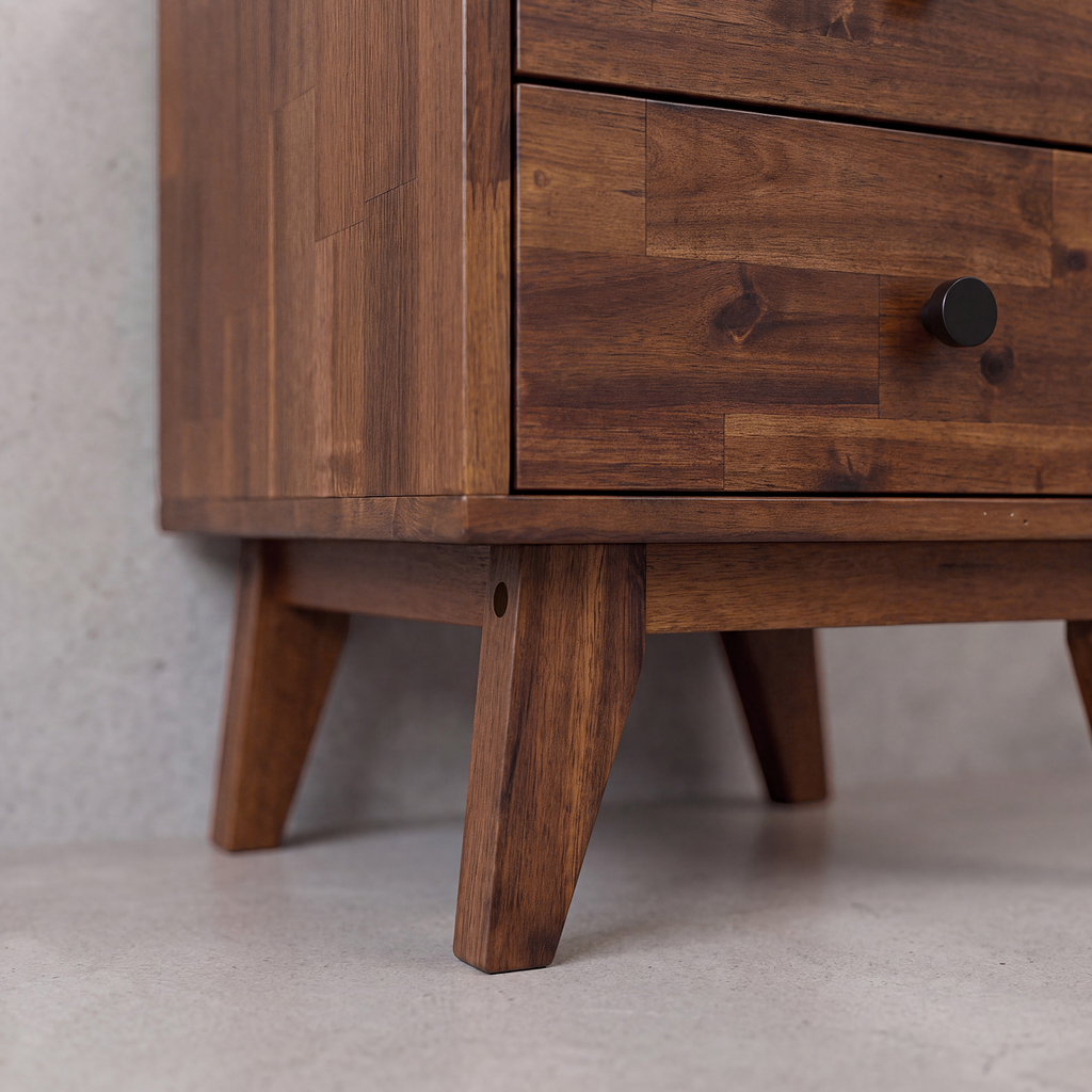 Close-up corner view of solid wood nightstand with drawer edge and tapered leg.