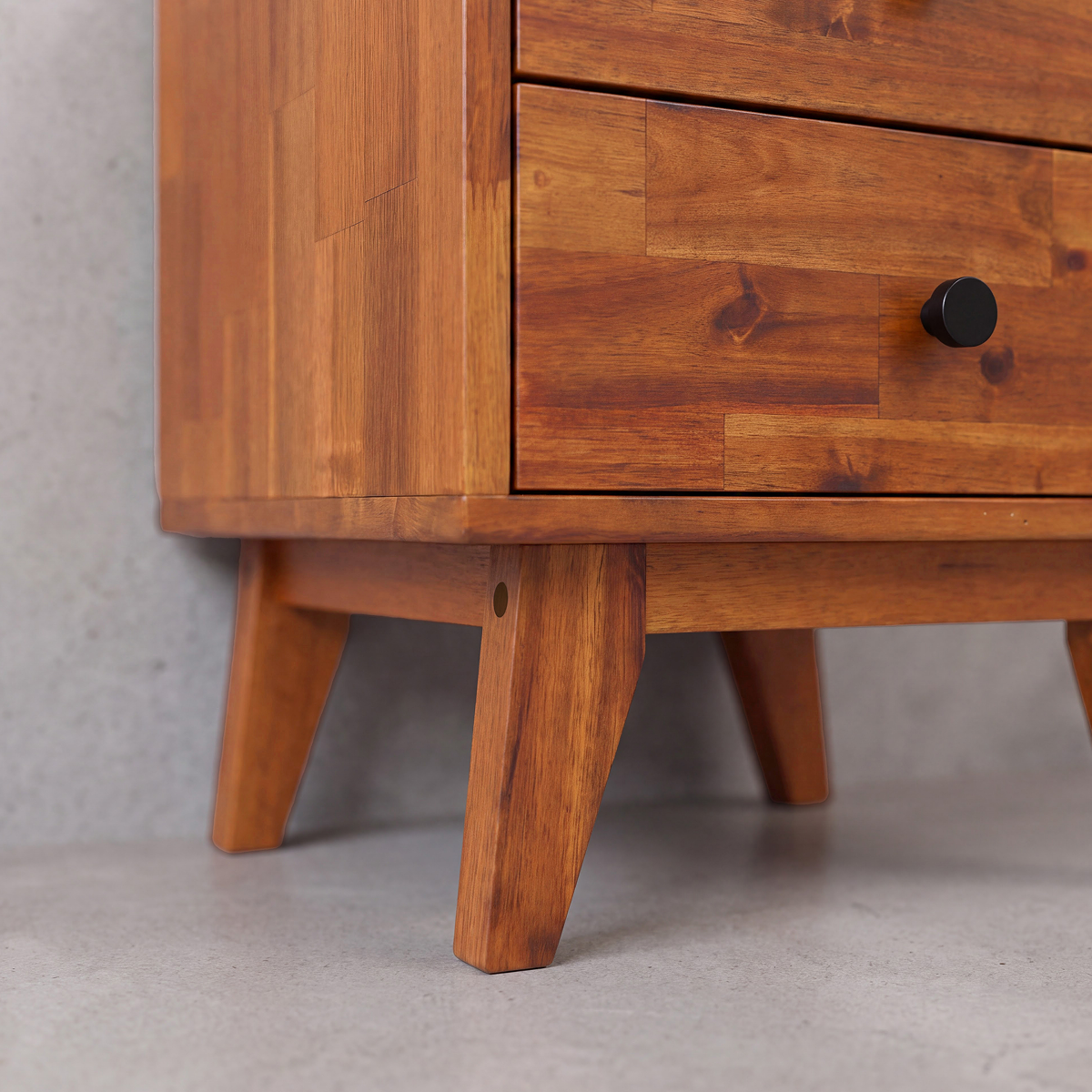 Silvia solid wood nightstand bottom corner view with tapered legs and drawer knobs