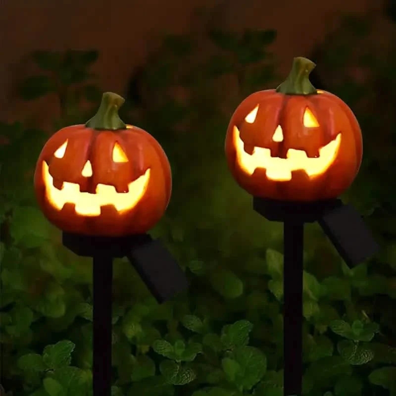 Two glowing orange jack-o'-lantern solar stake lights with carved pumpkins and green tops