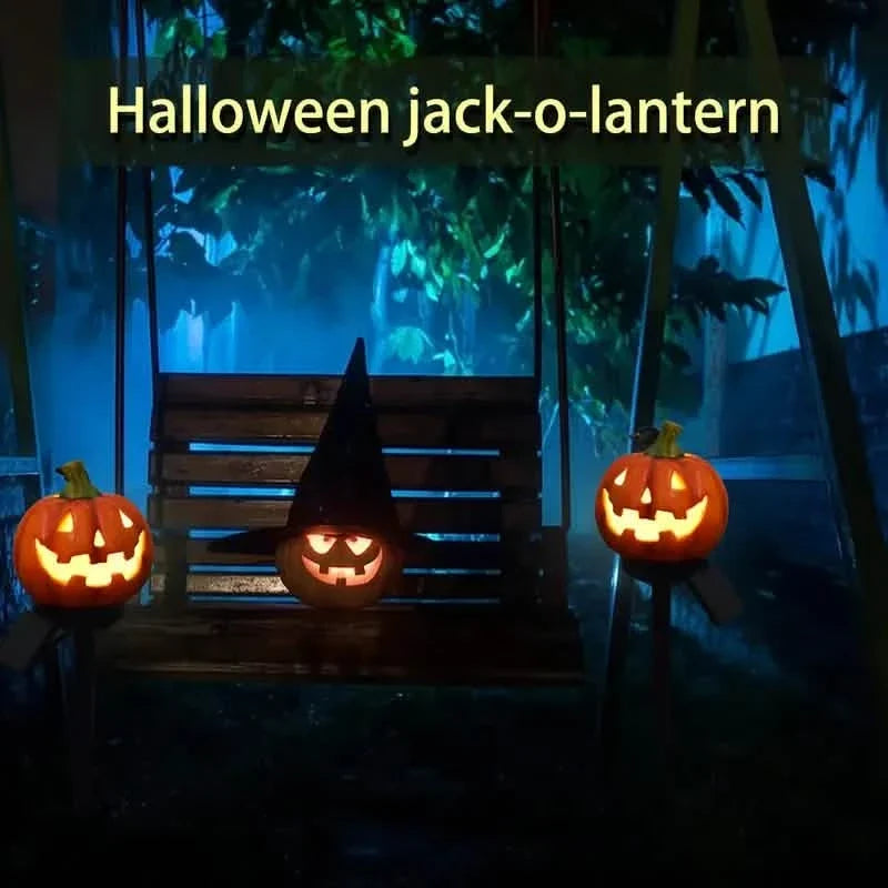 Set of jack-o'-lantern solar stake lights with glowing carved faces on yard path