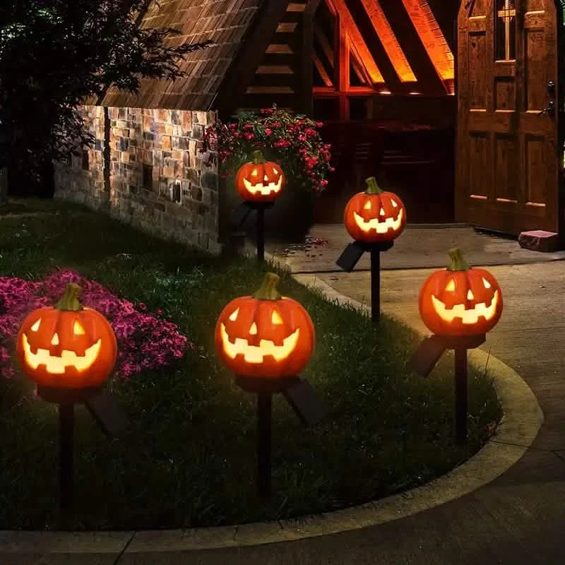 Several glowing jack-o'-lantern solar stake lights lining a garden walkway