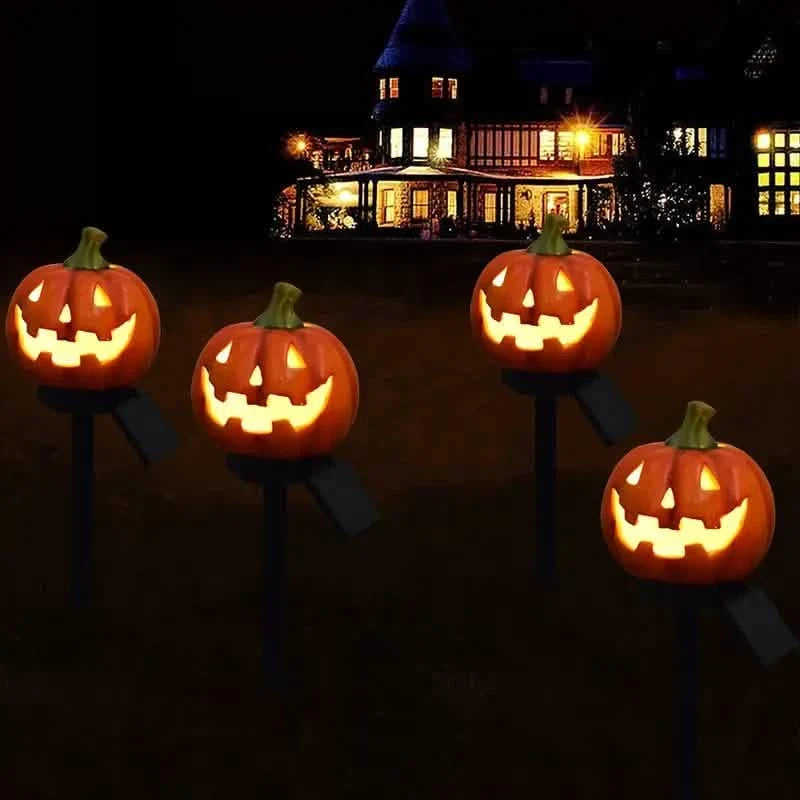 Group of glowing orange jack-o'-lantern solar stake lights in front yard at night