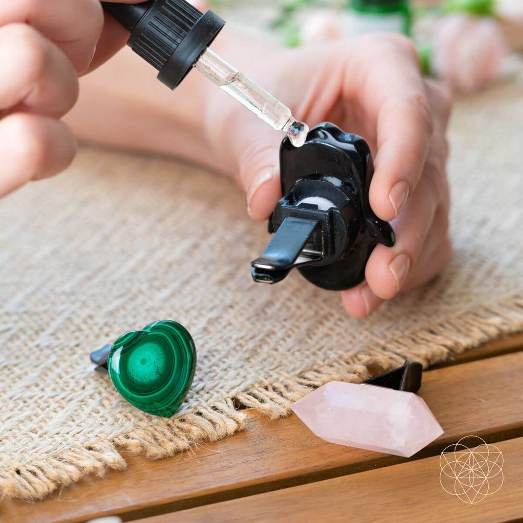 Black hamsa car diffuser being assembled on a tray with pink crystal wand and green heart
