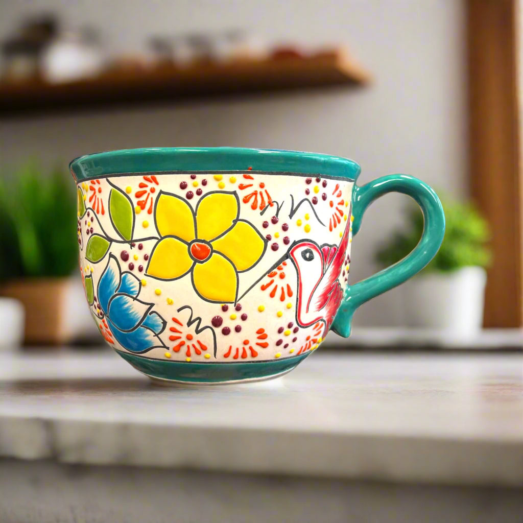 Hand-painted ceramic tea cup planter with green rim and multicolor flower and bird motif