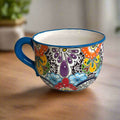 Hand-painted ceramic tea cup planter with blue handle and colorful floral butterfly design