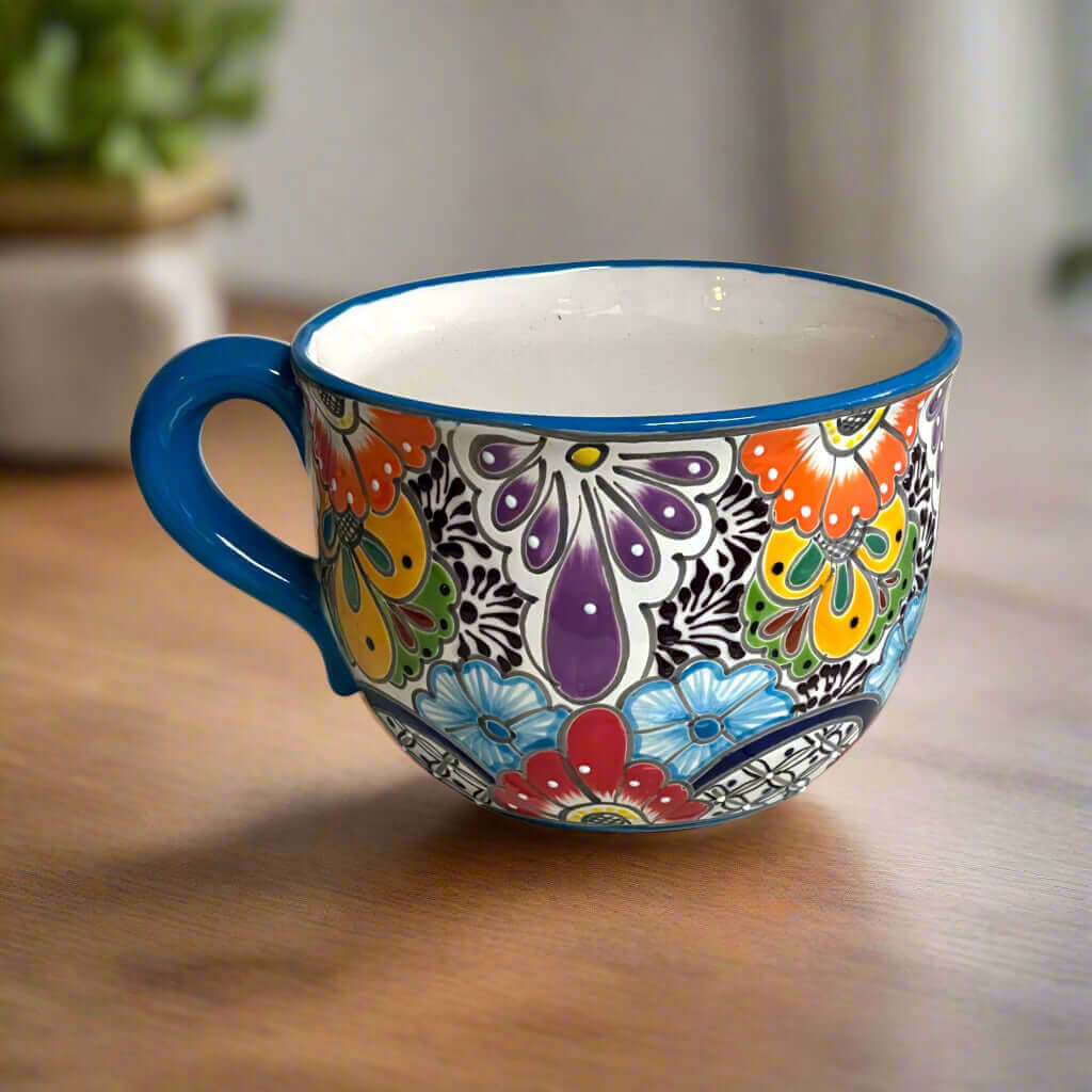 Hand-painted ceramic tea cup planter with blue handle and colorful floral butterfly design