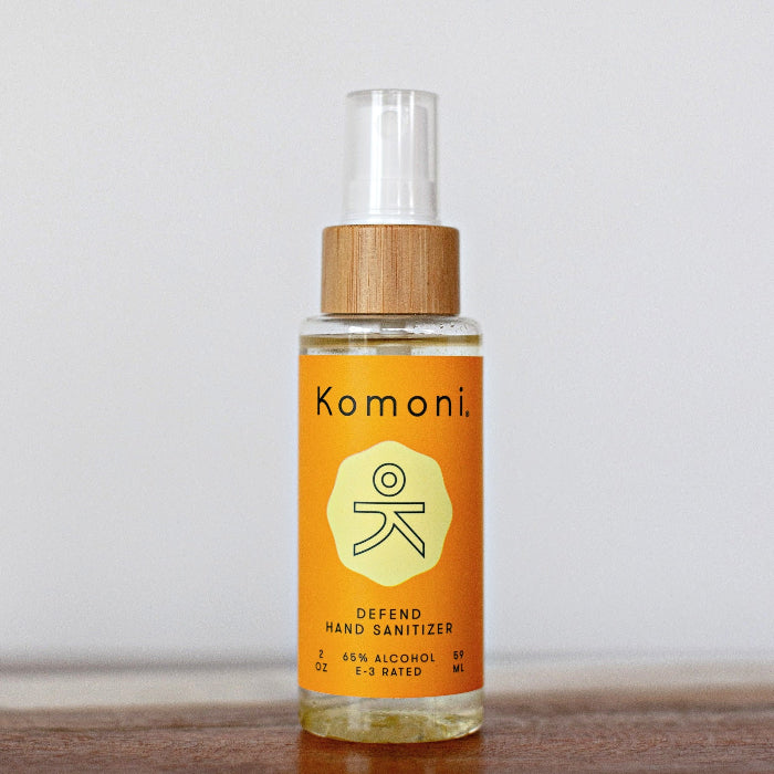 Instant hand sanitizer bottle in orange with clear spray cap and wood collar