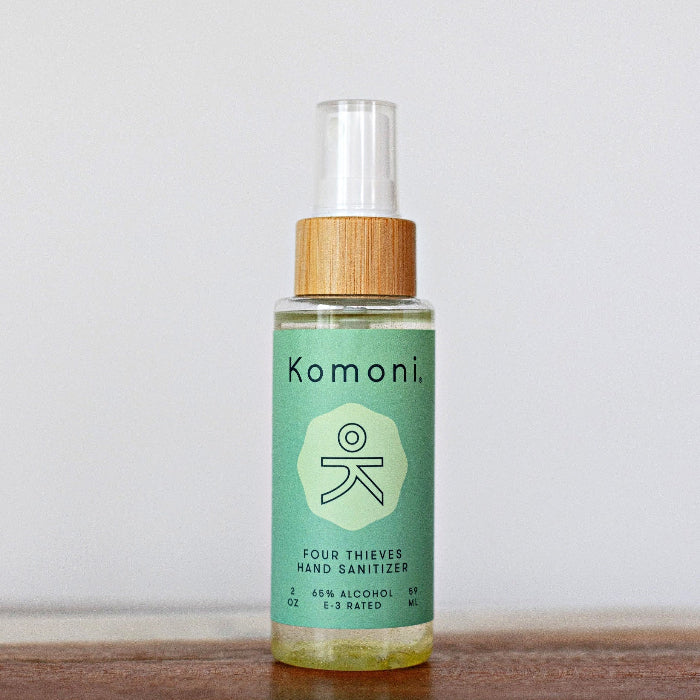 Instant hand sanitizer bottle in green with clear spray cap and wood collar
