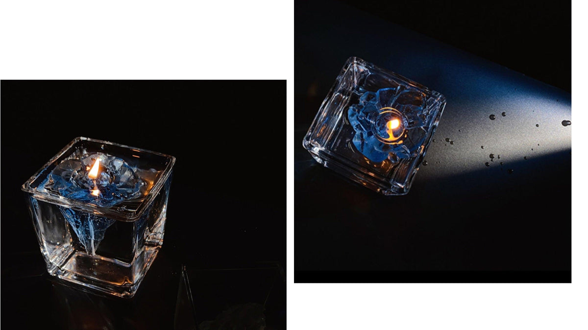 Blue iceberg-shaped candle in clear cube holder with lit wick