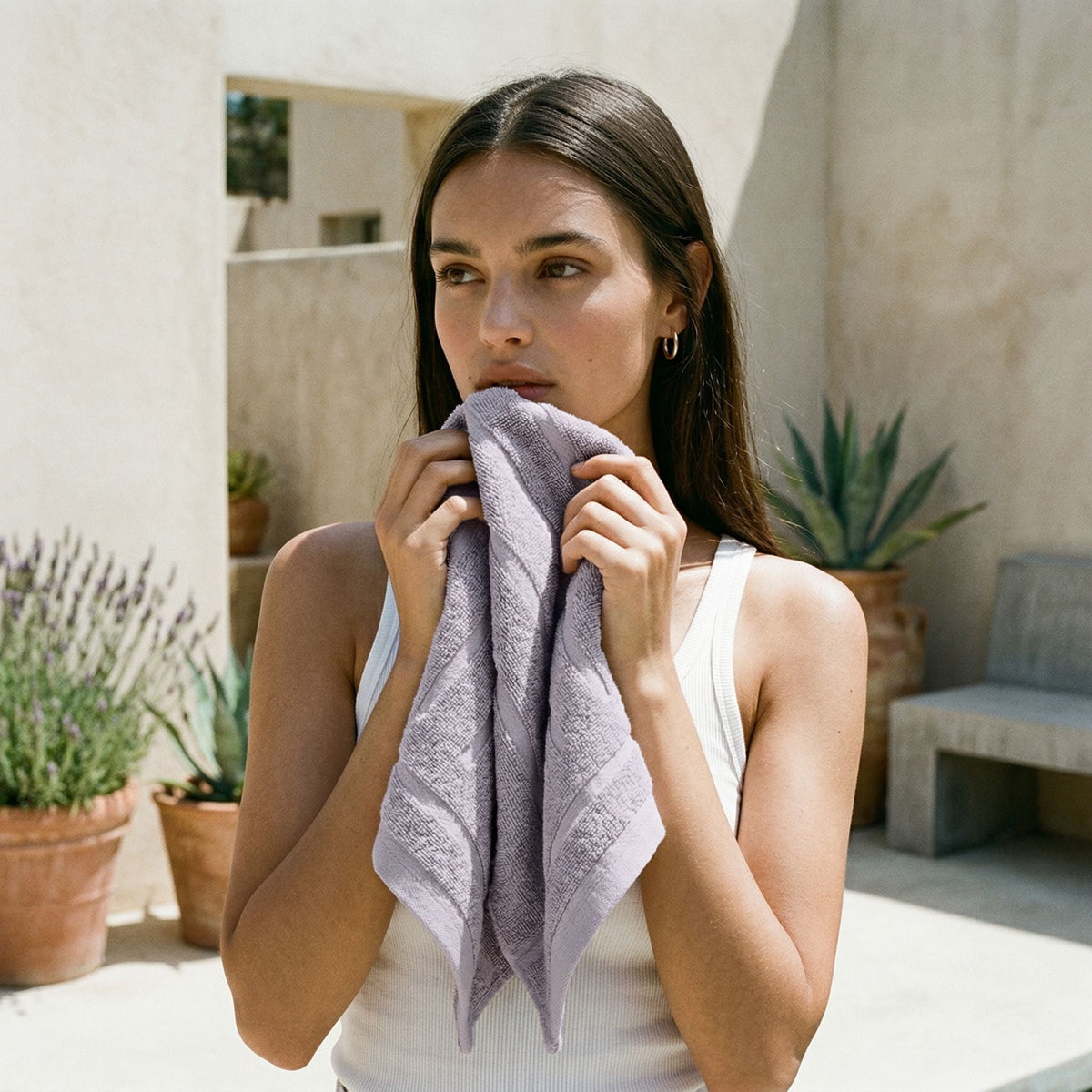 Lilac cotton towel, folded and held to face by person in white top