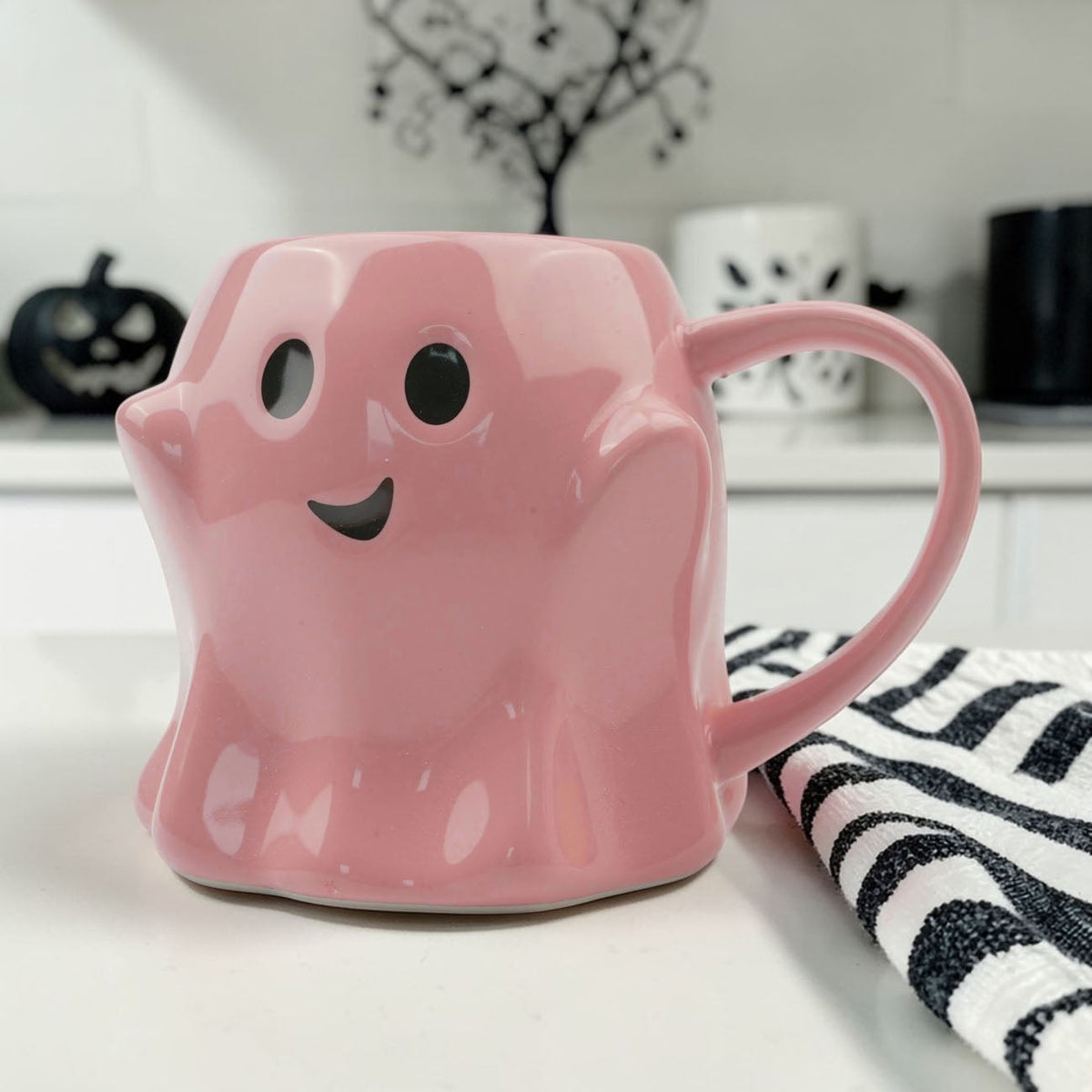 Pink ghost-shaped mug with black eyes and a smiling face