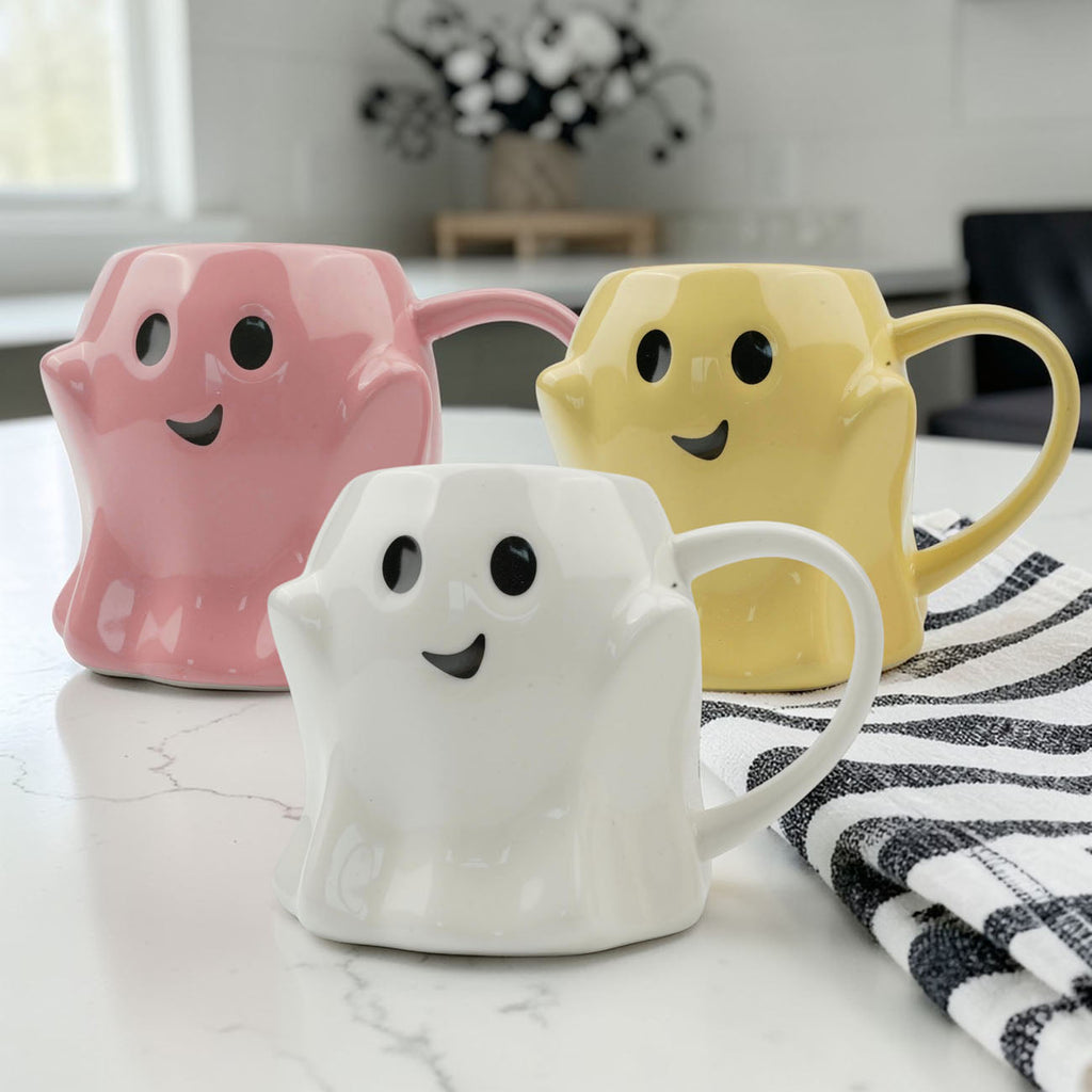Set of ghost-shaped ceramic mugs in pink, yellow, and white, each with smile face