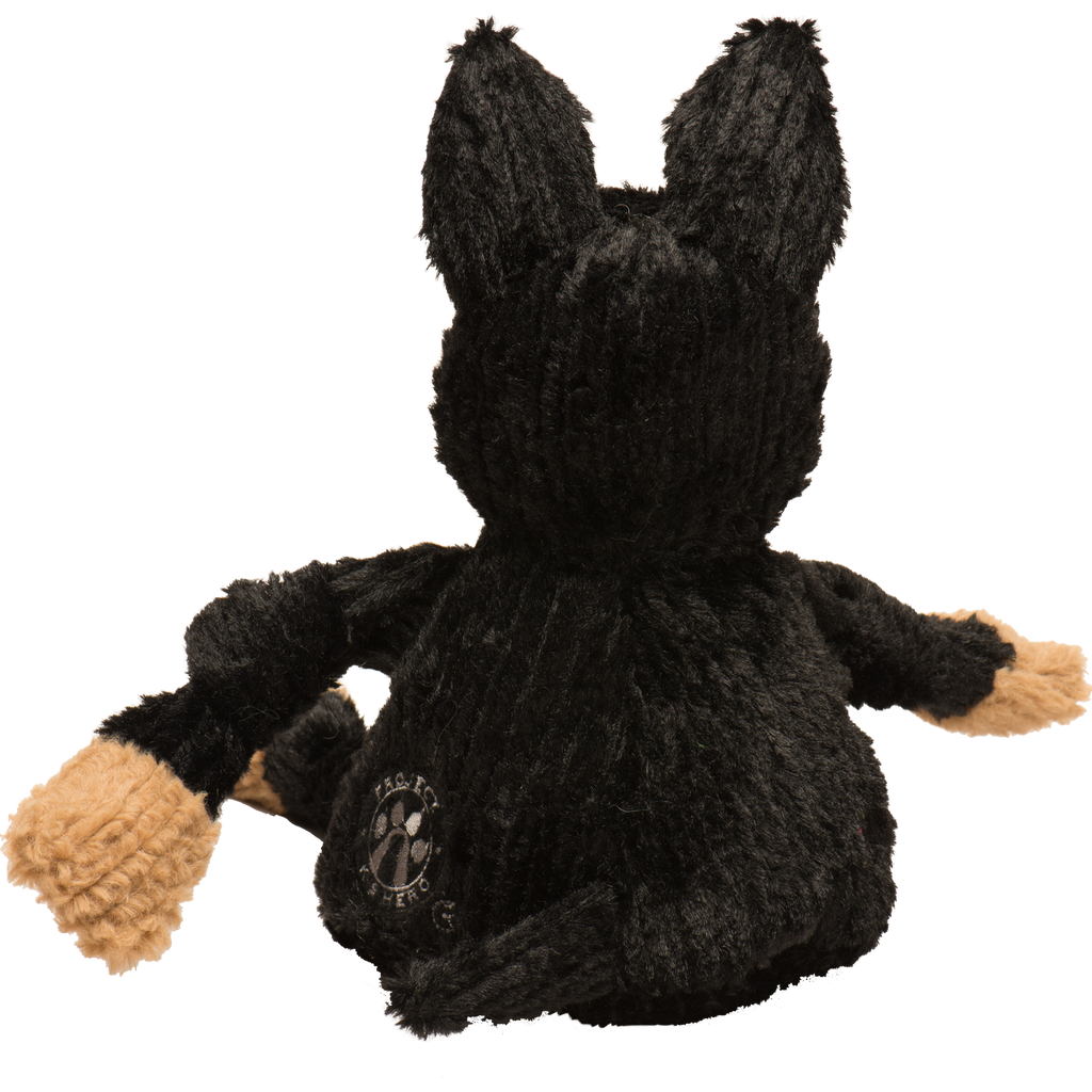 Black plush dog toy with upright ears, tan muzzle paws, and circular chest emblem