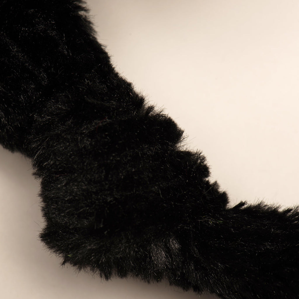 Black plush dog toy back leg with fuzzy texture