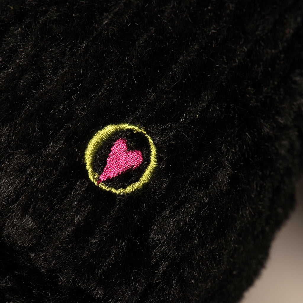 Black plush dog toy with round neon-accent emblem patch on shoulder