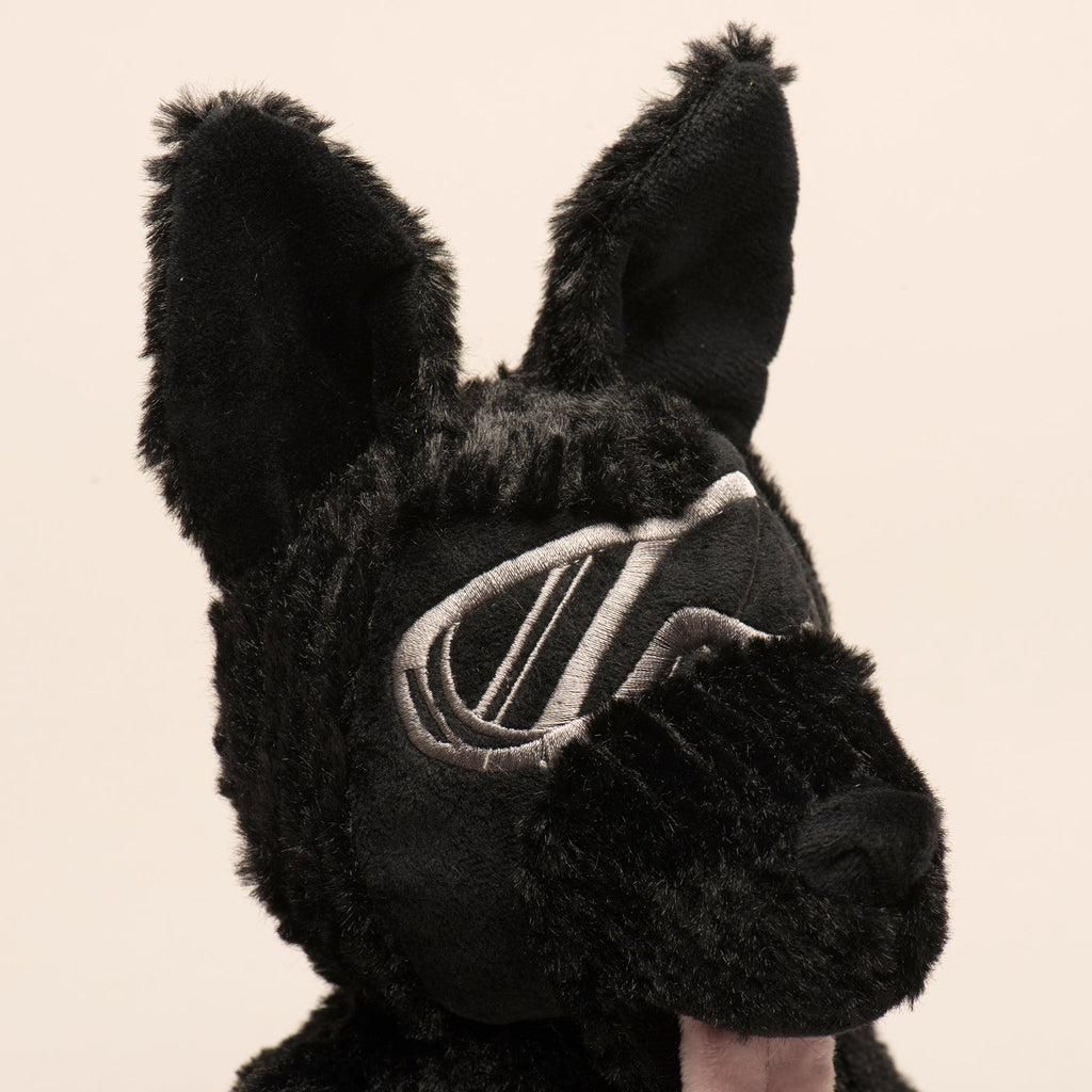 Black plush dog toy head and chest detail with embroidered shield emblem