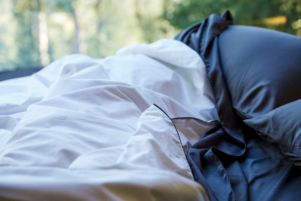 Silk-filled duvet set in white with dark piping, with visible layered folds