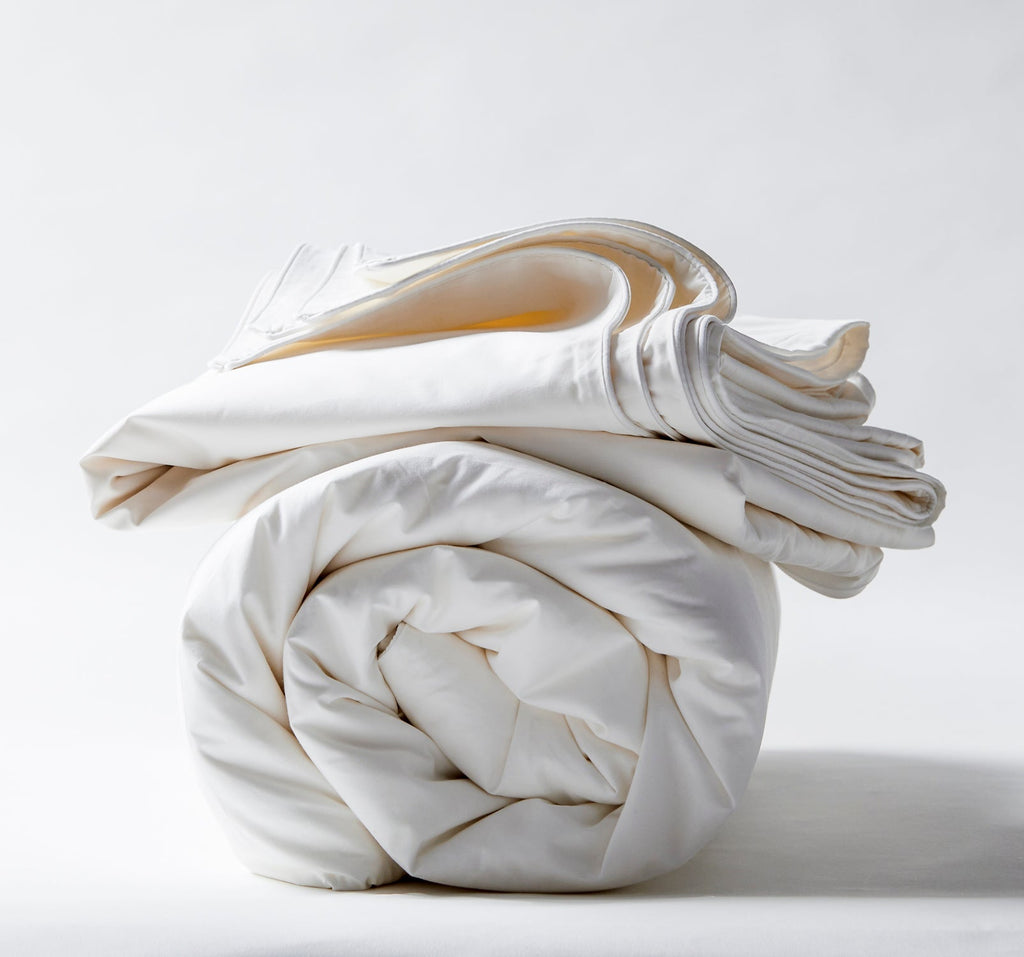 White silk-filled duvet folded into a compact roll with layered creases