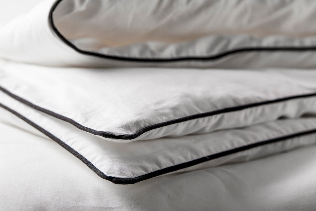 White duvet with dark piping along the seam edge, close-up view
