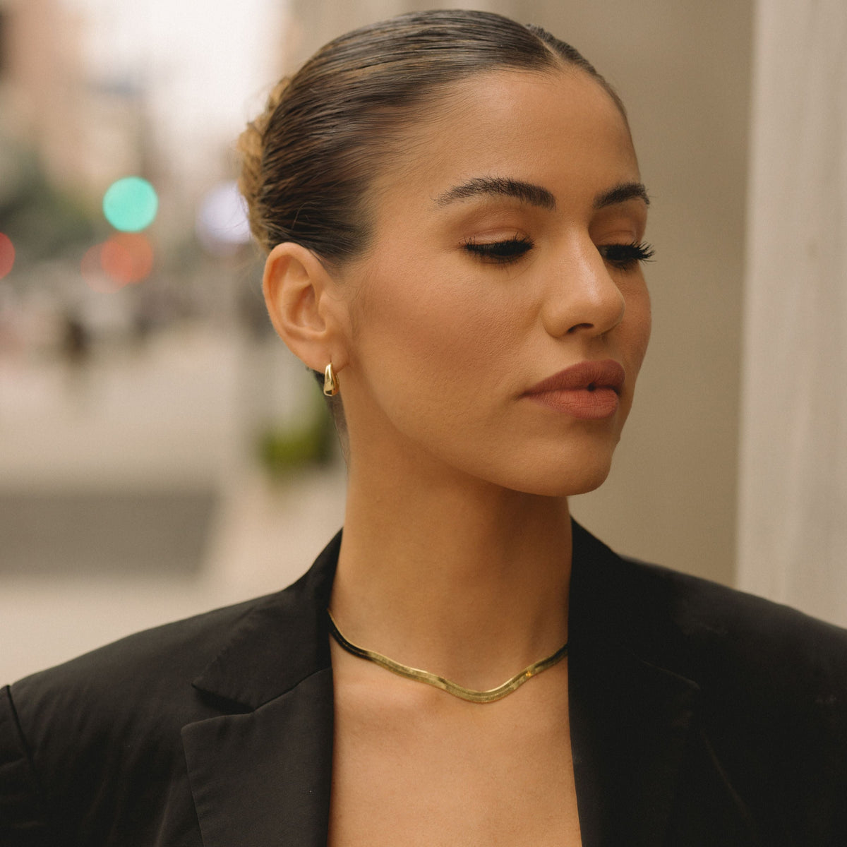 Gold herringbone chain necklace worn close to the collarbone