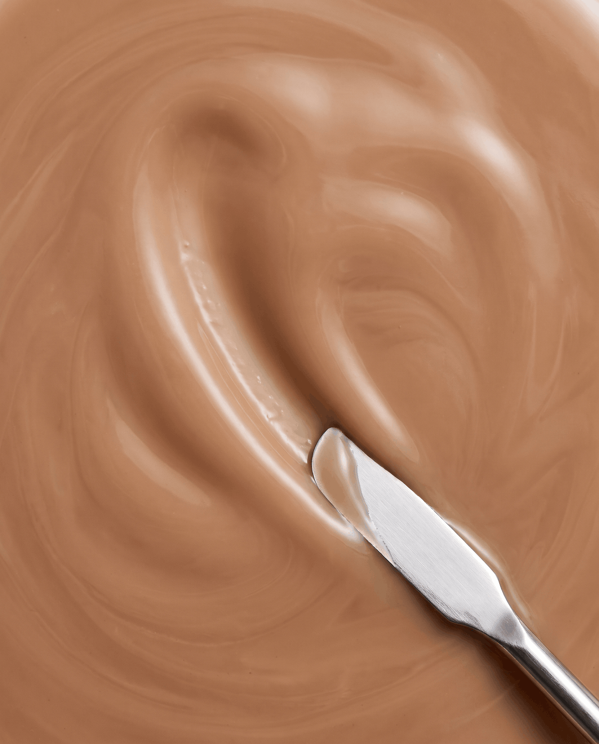 Instant bronzing serum swatch in tan on applicator spoon