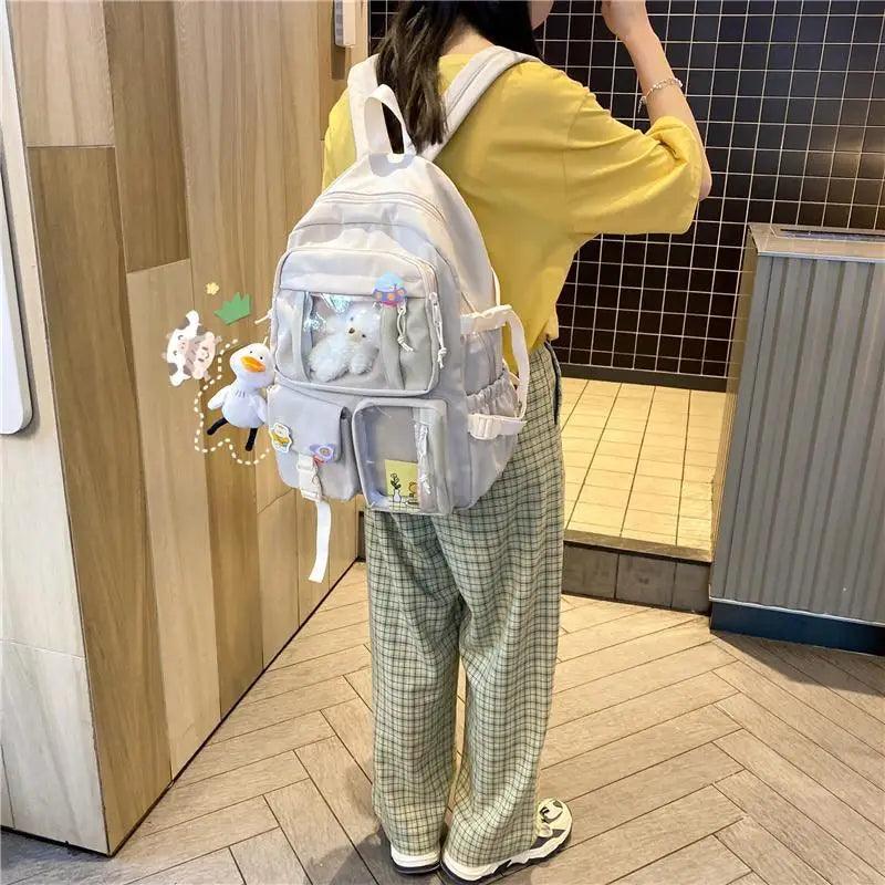Light cream nylon backpack with front pockets and plush keychain charm