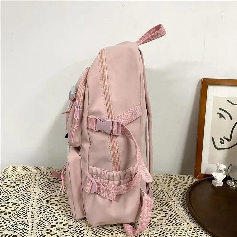 Blush pink nylon backpack with side straps, front pocket panel, cute plush bear detail