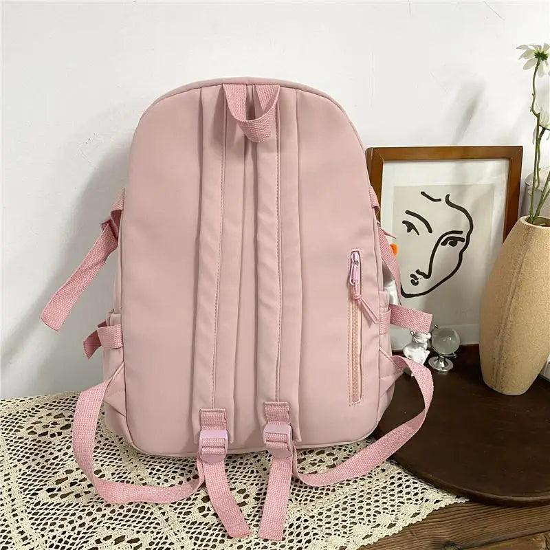Pink nylon backpack with padded straps and side pocket, simple front design