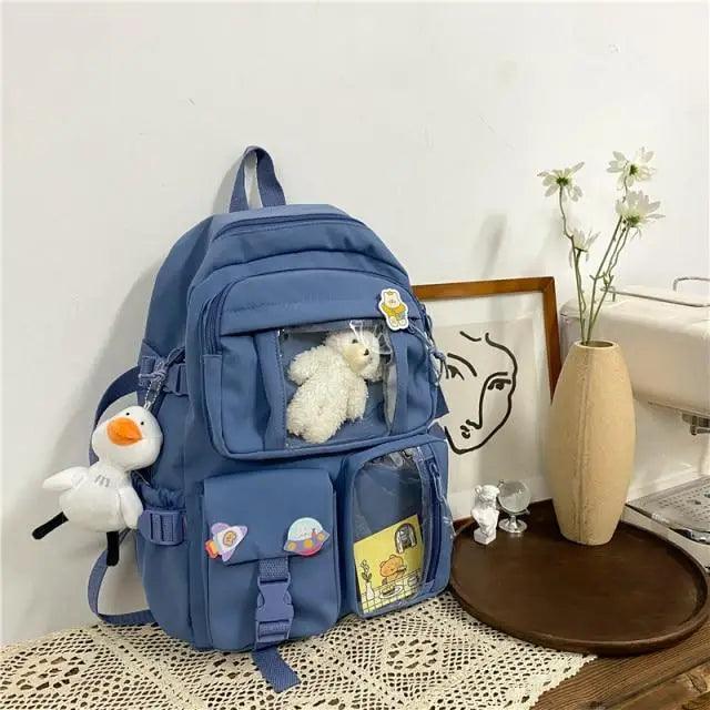 Blue nylon backpack with front pockets and plush animal accessory